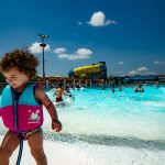 2019_KahunaWavePool_LittleGirl_SmilingWalkingAwayFromWater_1080